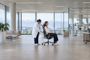 Ergonómiai szakember irodai széket állít be egy modern munkahelyen.